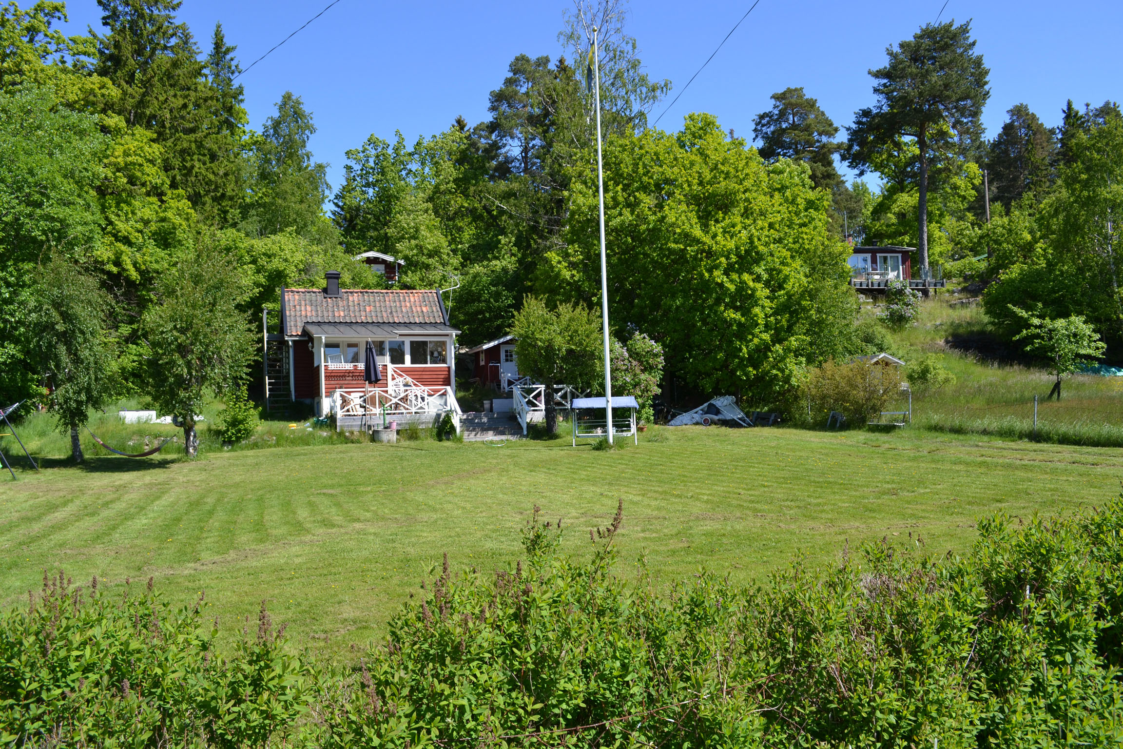 Stugan med omgivande trädgård sedd från Abborrkroksvägen.