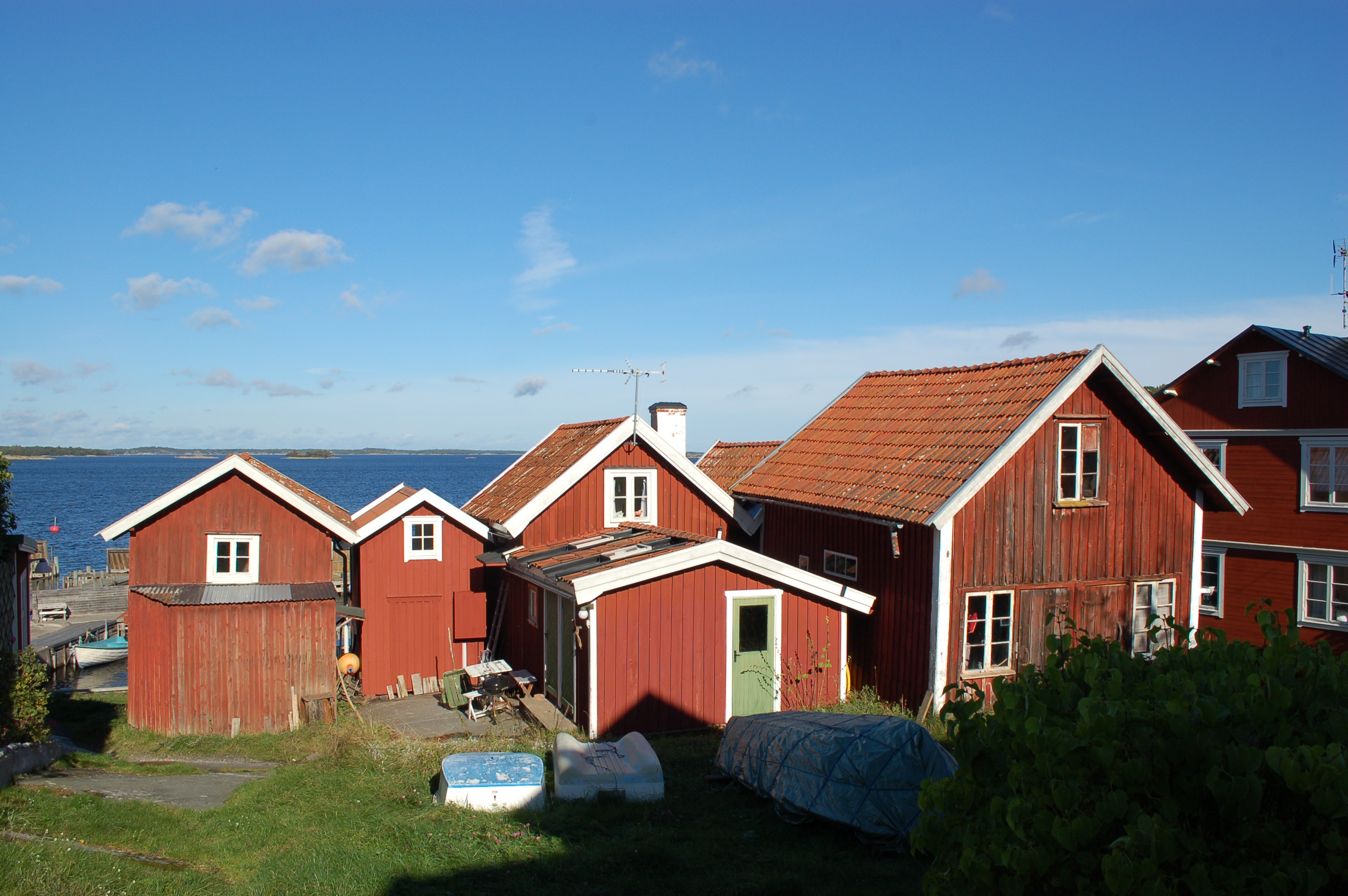 Översiktsbild. De två bodarna som utgör denna byggnad synd längst bort till höger i bild: Boden med vitputsad skorsten samt den bod vars tak skymtas intill den.