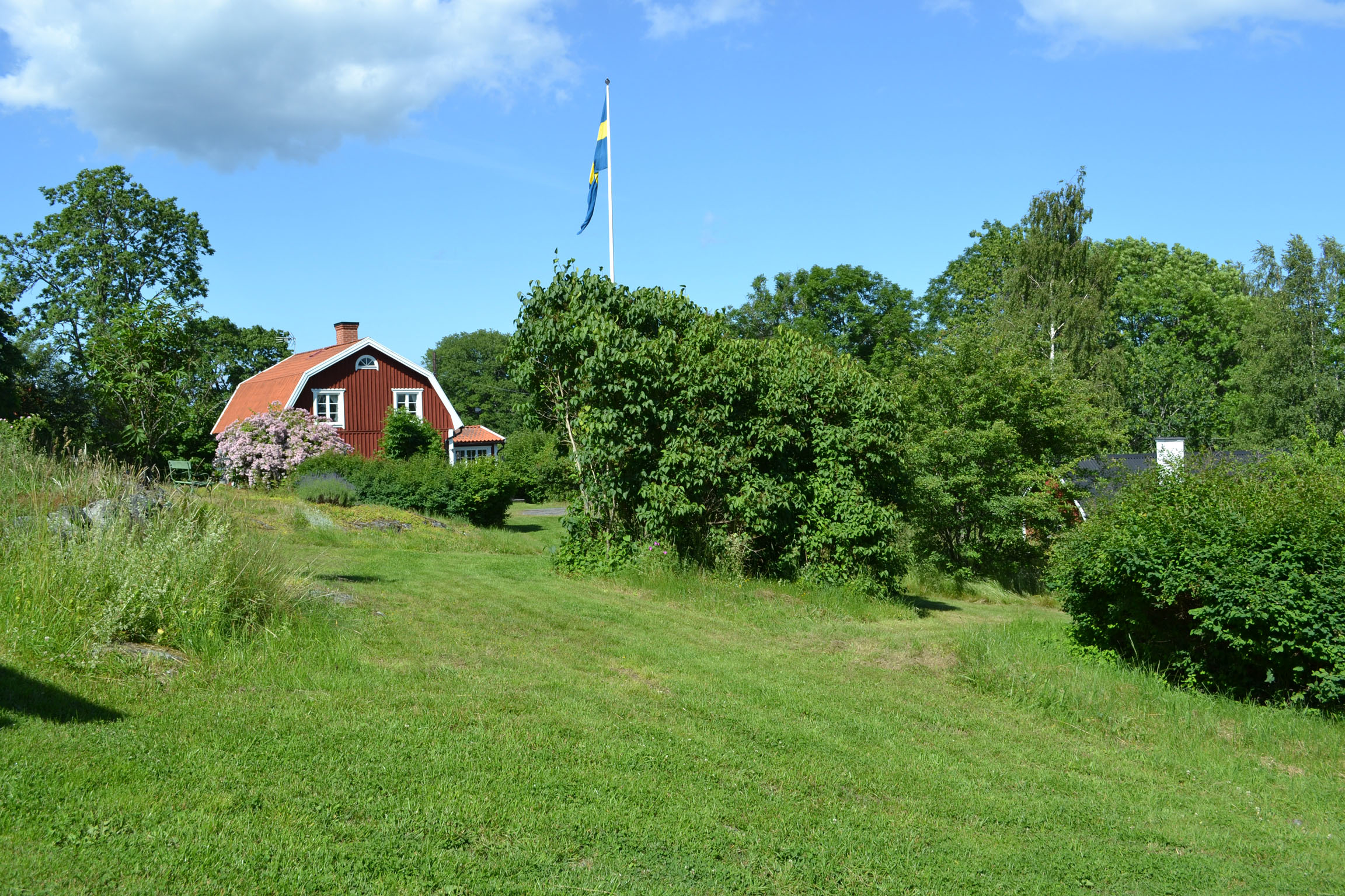 Bostadshus med omgivande trädgård sett från söder.