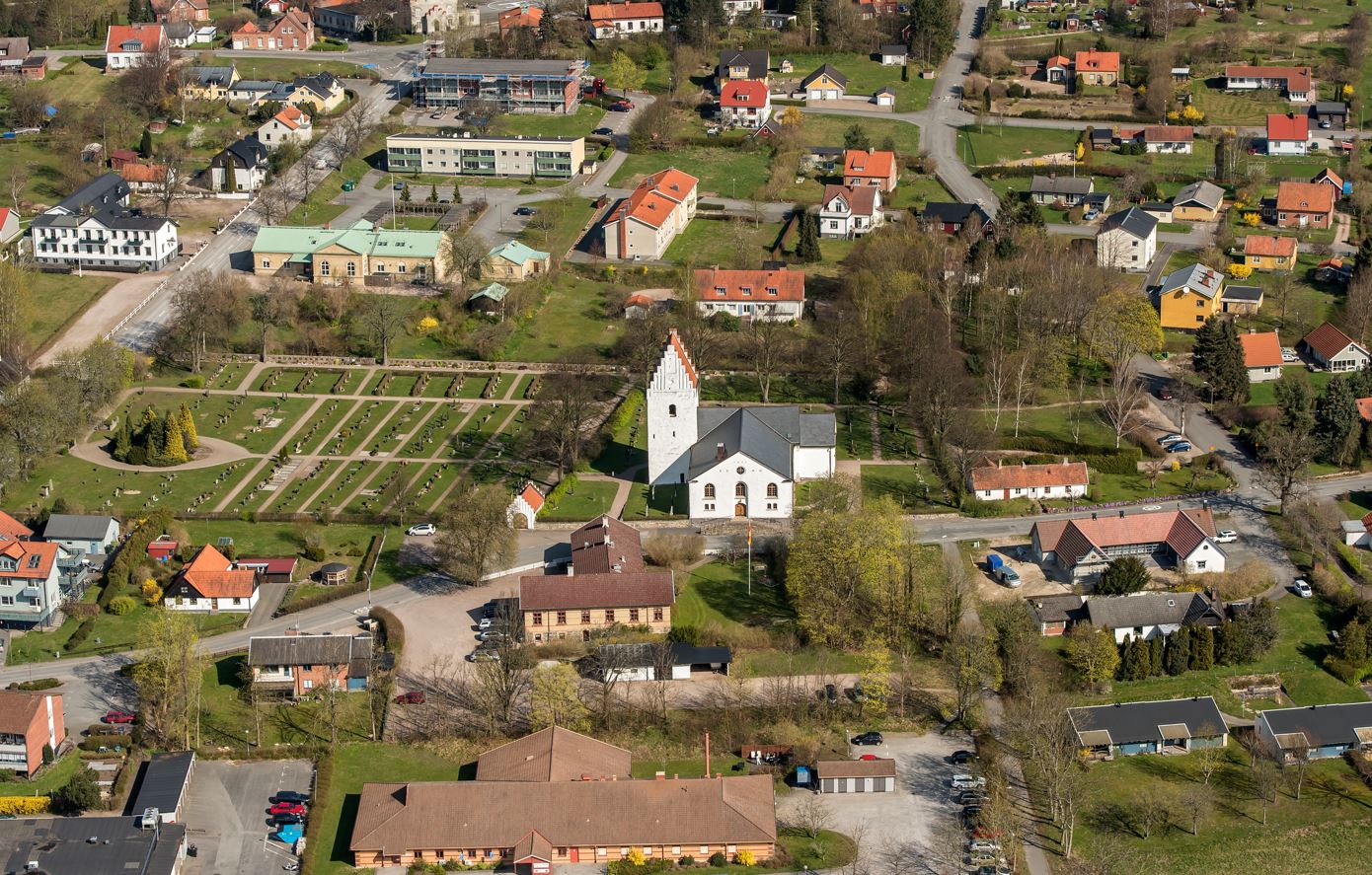 Flygbild över Degeberga kyrkoanläggning från söder med väg 19 i vänster i bild och vägen mot Vittskövle som passerar söder om kyrkan.