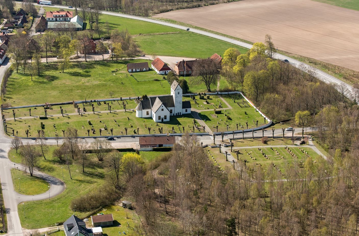 Flygbild över Everöds kyrkoanläggning från norr med den före detta prästgården i sydväst och den äldre vägsträckningen öster om kyrkogården.