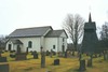 Kyrkan, klockstapeln och en del av kyrkogården från nordväst. 