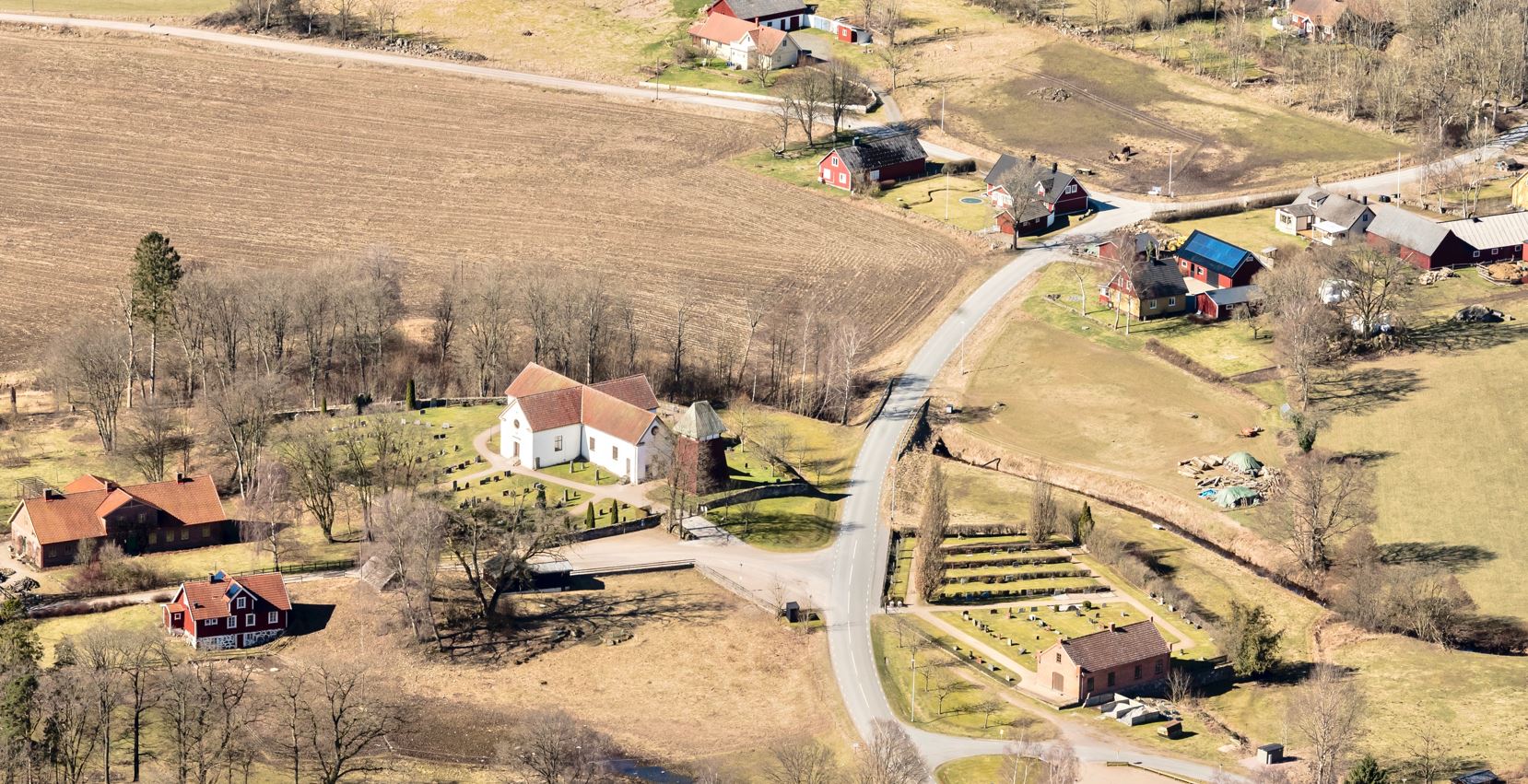 Flygbild över Brönnestad 2014, tagen från sydost. Landsvägen passerar mellan gamla och nya
kyrkogårdarna, vidare mot det gamla bycentrat norr om kyrkan.