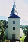Västfasaden på Hulareds kyrktorn sedd från den privata begravningsplatsen väster om kyrkan.
