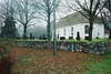 Hillareds kyrka med omgivande kyrkogård och klockstapel, från NÖ.
