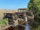 Dammens två utskov mellan murade pelare i sten. På pelarna finns mindre pågjutningar i 
betong.  