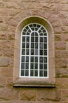 Östra fönstret i koret på Vänga kyrka är igenmurat från insidan och glaset har svärtats på utsidan.