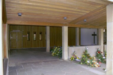 Entrén till kontor och Evighetens kapell i krematoriet på S:t Sigfrids griftegård. Korset till höger i bild är ett fönster till Minnets kapell i suterrängvåningen.