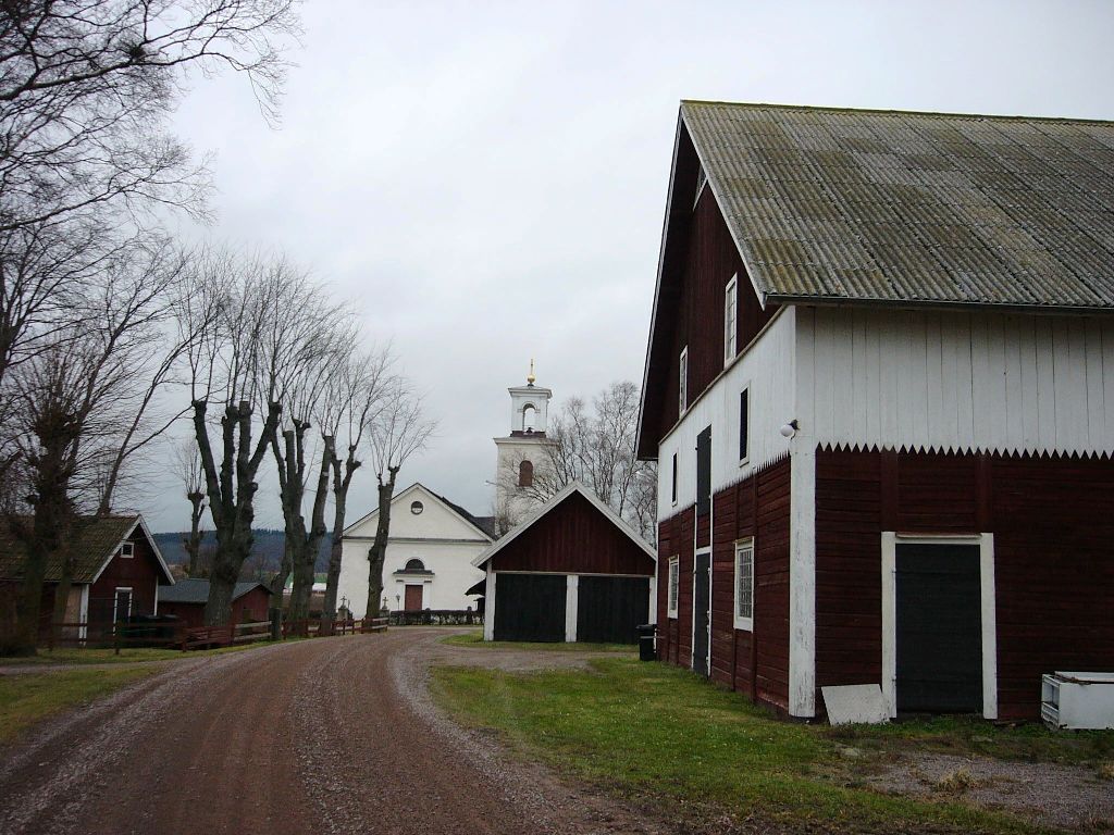 Kyrkan från söder med f d löneboställets ekonomibyggnader i förgrunden.