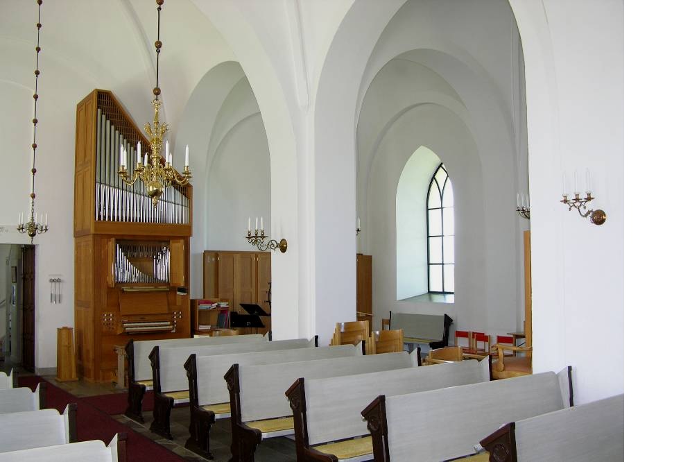 Kyrkorummet
"Till de senaste inslagen i kyrkorummet hör bänkinredningens ljusgrå ryggar och säten från 1988, norra korsarmens lösa stolar, samt orgeln längst bak".