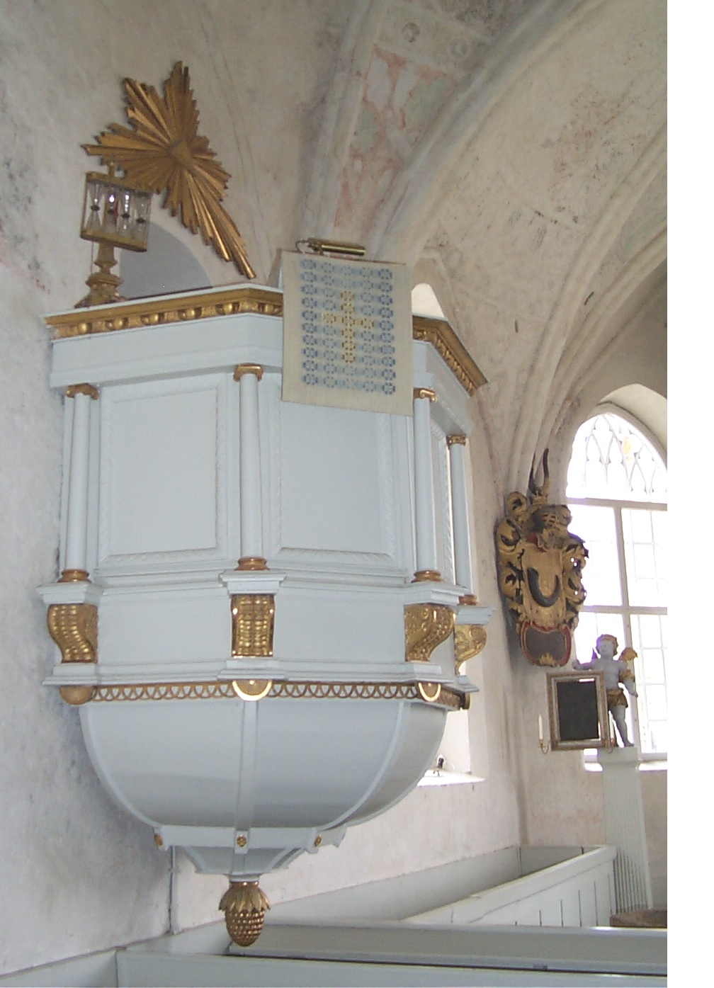 Predikstolen på norra sidan har femsidig korg prydd med kolonner och snidade, förgyllda ornament
