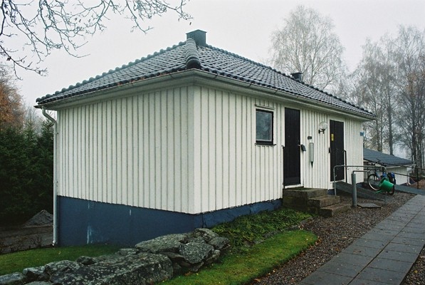 Bårhus, förråd och vaktmästarkontor vid norra kyrkogårdsmuren vid Gällstads kyrka, från SV.

